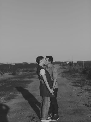 Couple sharing a kiss on a dirt road in black and white desert landscape photo.