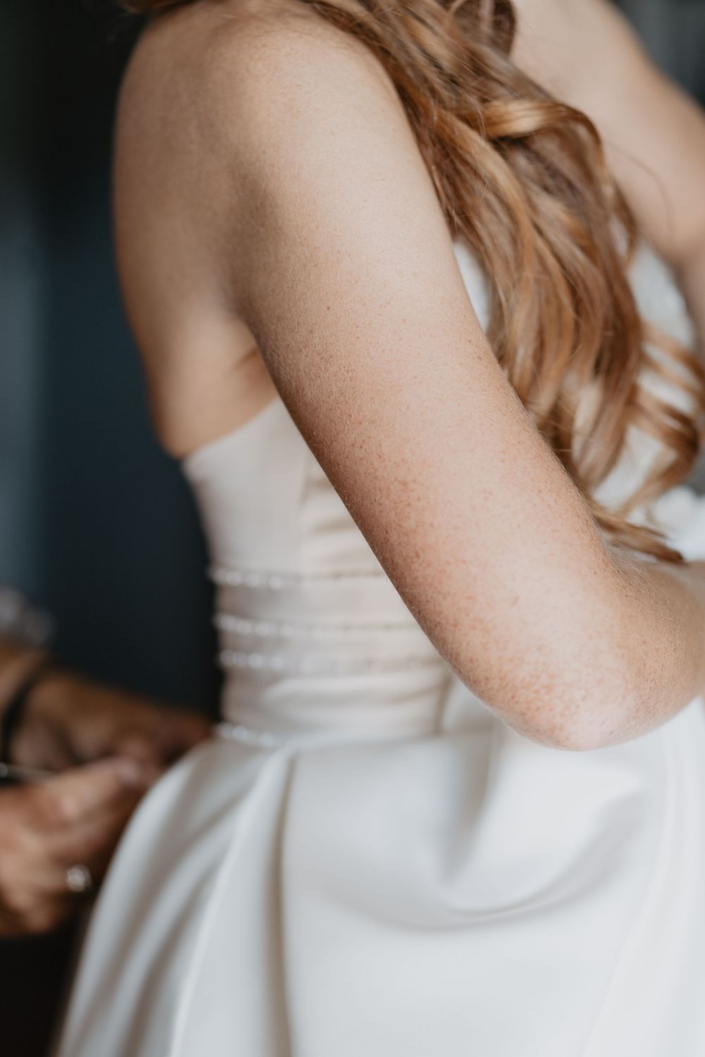 Close-up of bride in strapless white satin wedding dress with flowing wavy hair.