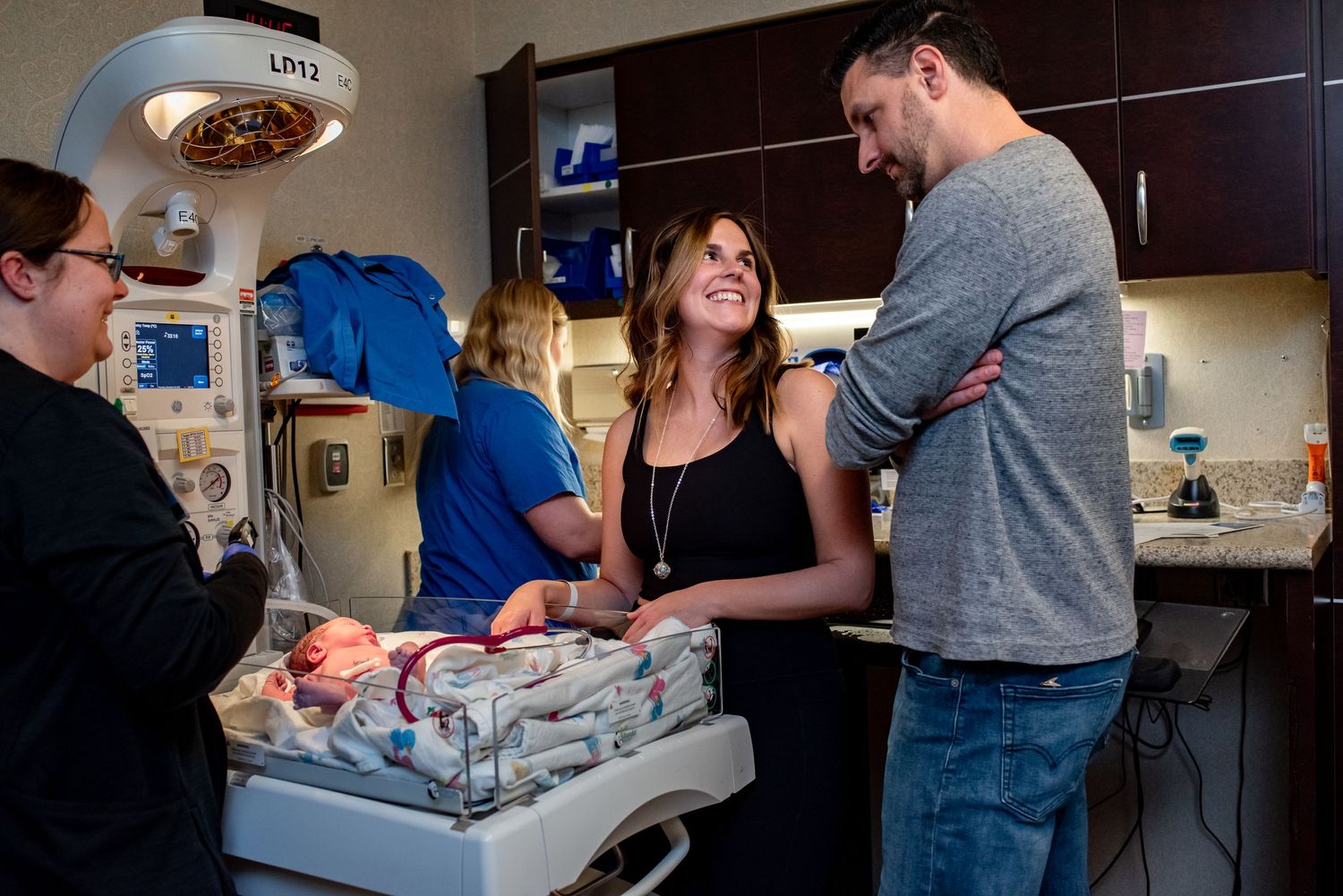 Medical staff and parents gather around a hospital bed during a joyful moment with a newborn.