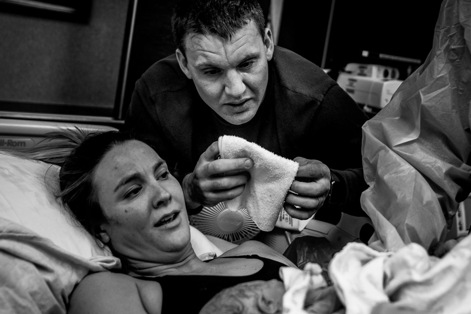Black and white image capturing raw emotion during childbirth in hospital setting.