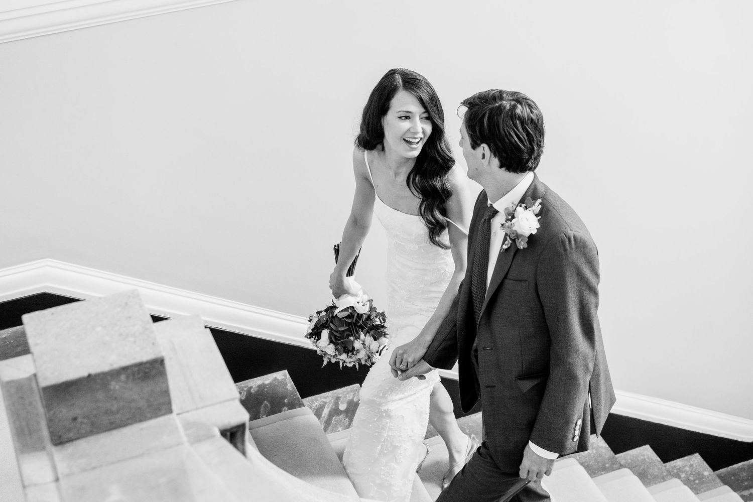 Groom tosses confetti at elegant indoor wedding reception with Edison bulb lighting and disco ball.