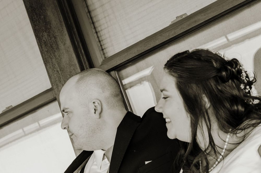 Black and white photo of a bald man in a suit and a woman with updo hairstyle at a wedding ceremony.
