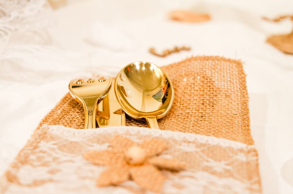 Gold wedding rings and key on burlap and lace fabric with floral decorations.