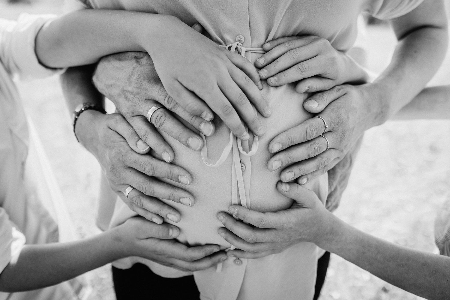 Eine vierköpfige Familie sitzt während eines Fotoshootings im Freien an einem freundlichen Tag auf einer Wiese zusammen.