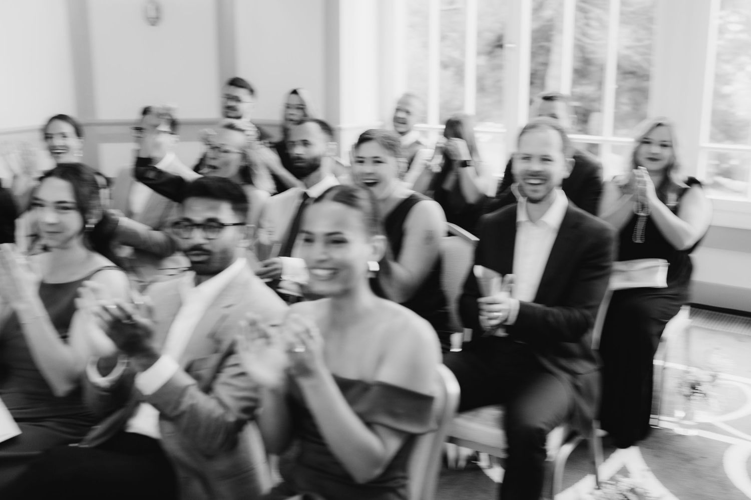 Guests clapping and smiling at a formal event in black and white photography.