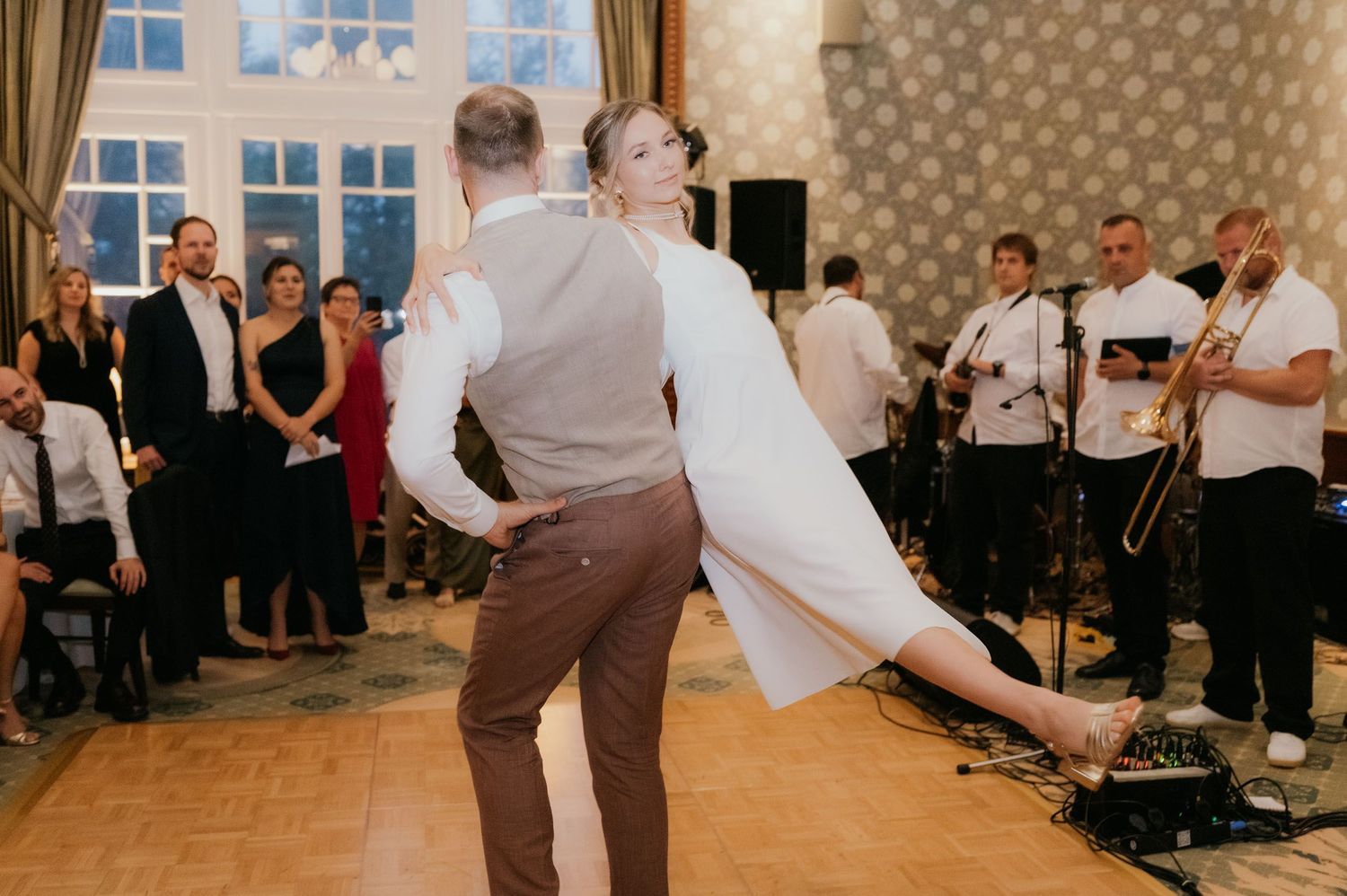 Bride and groom dancing together at wedding reception with live band performing.