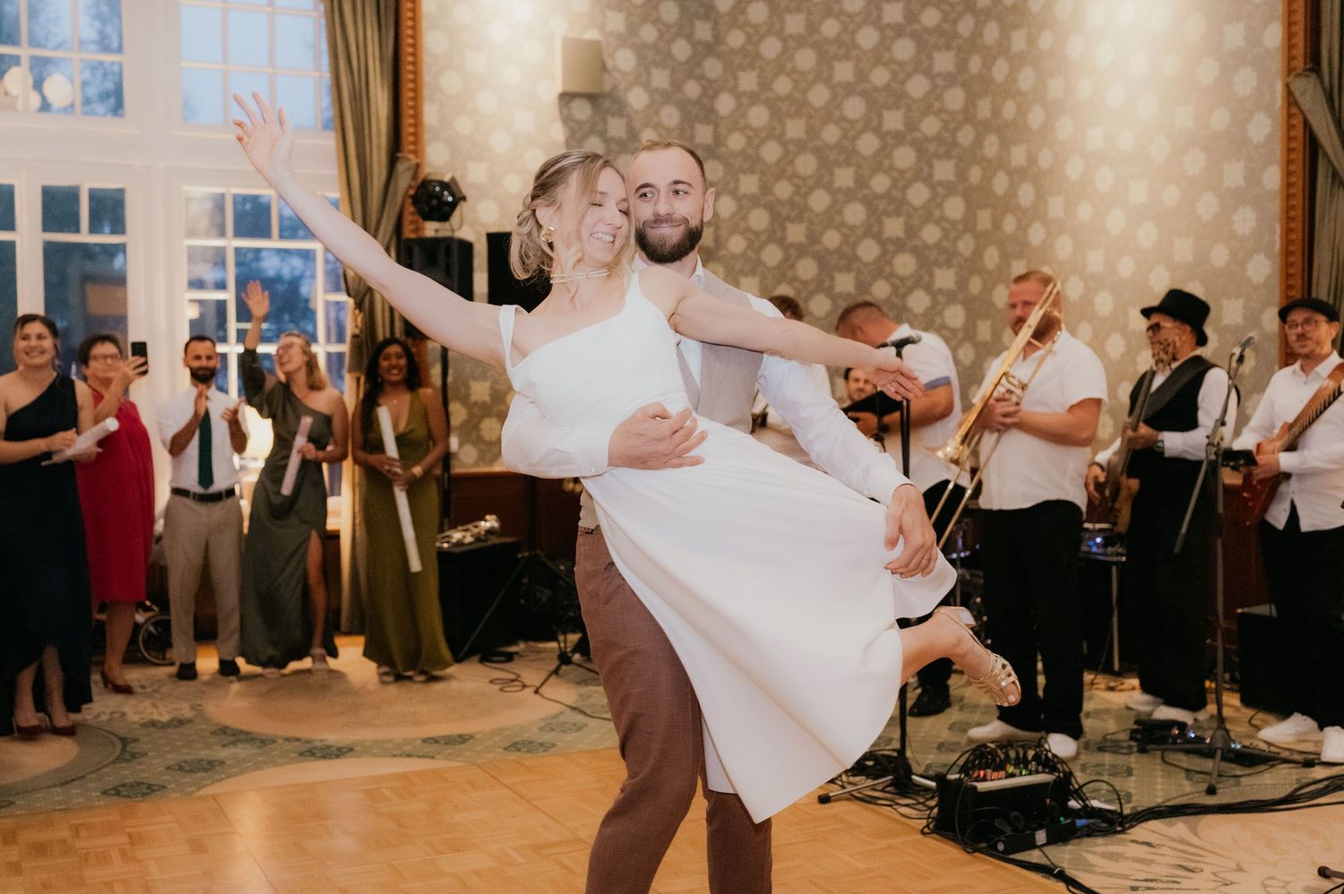 Bride and groom share first dance at wedding reception with live band performing in elegant ballroom.