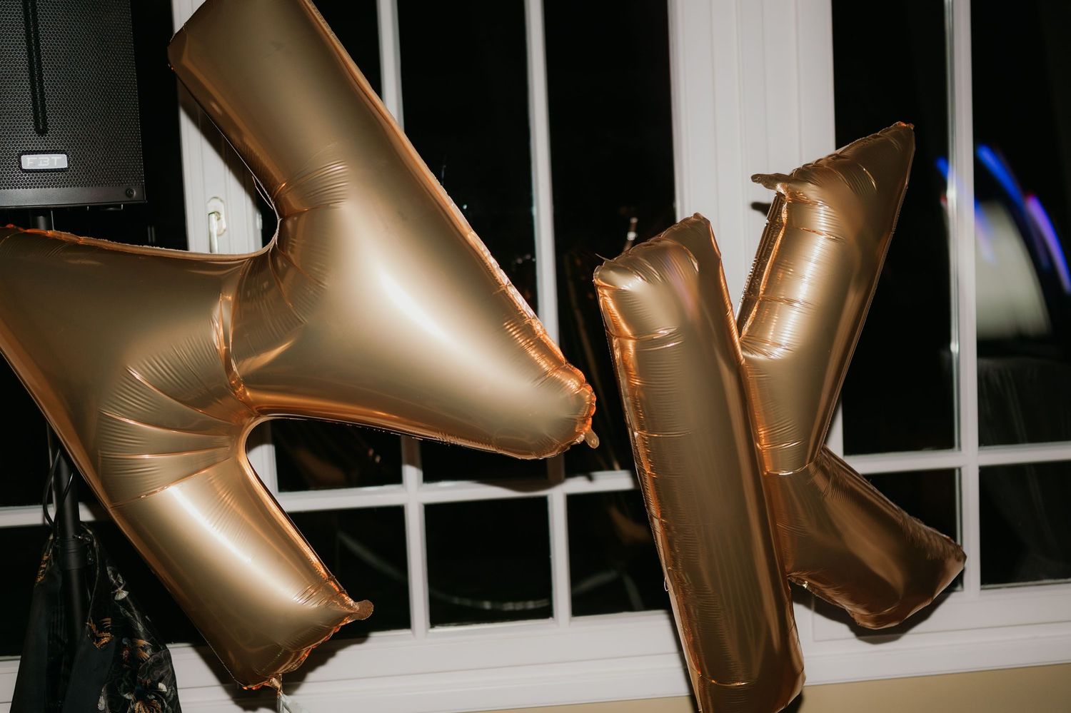 Rose gold metallic letter balloons spelling initials displayed at a wedding reception celebration event.