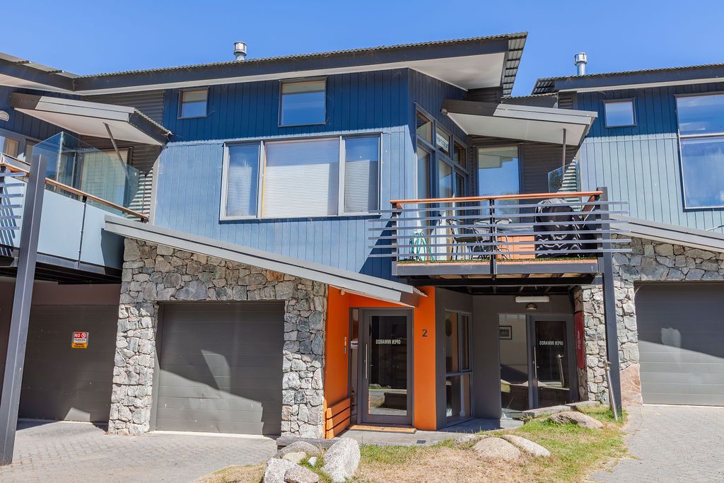 Modern hillside homes with stone accents and large windows showcase contemporary architectural design in a residential setting.