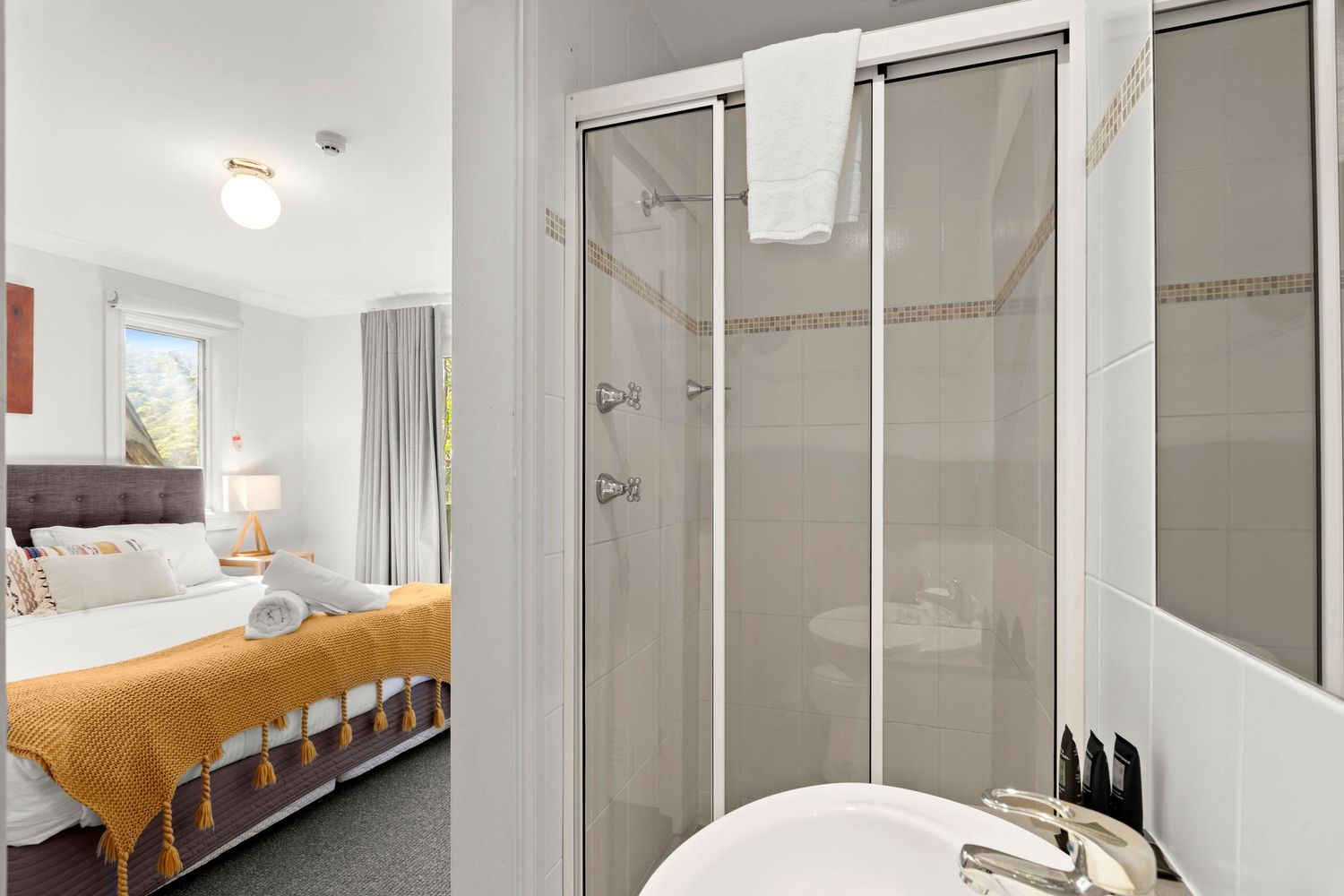 Modern minimalist bathroom features white tiles, glass shower enclosure, and sleek fixtures in a clean, bright design.