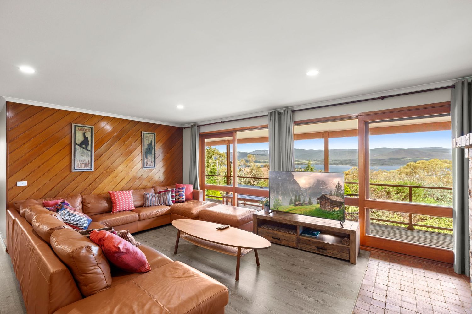 Panoramic view of a modern living room with floor-to-ceiling windows overlooking a scenic mountain landscape.