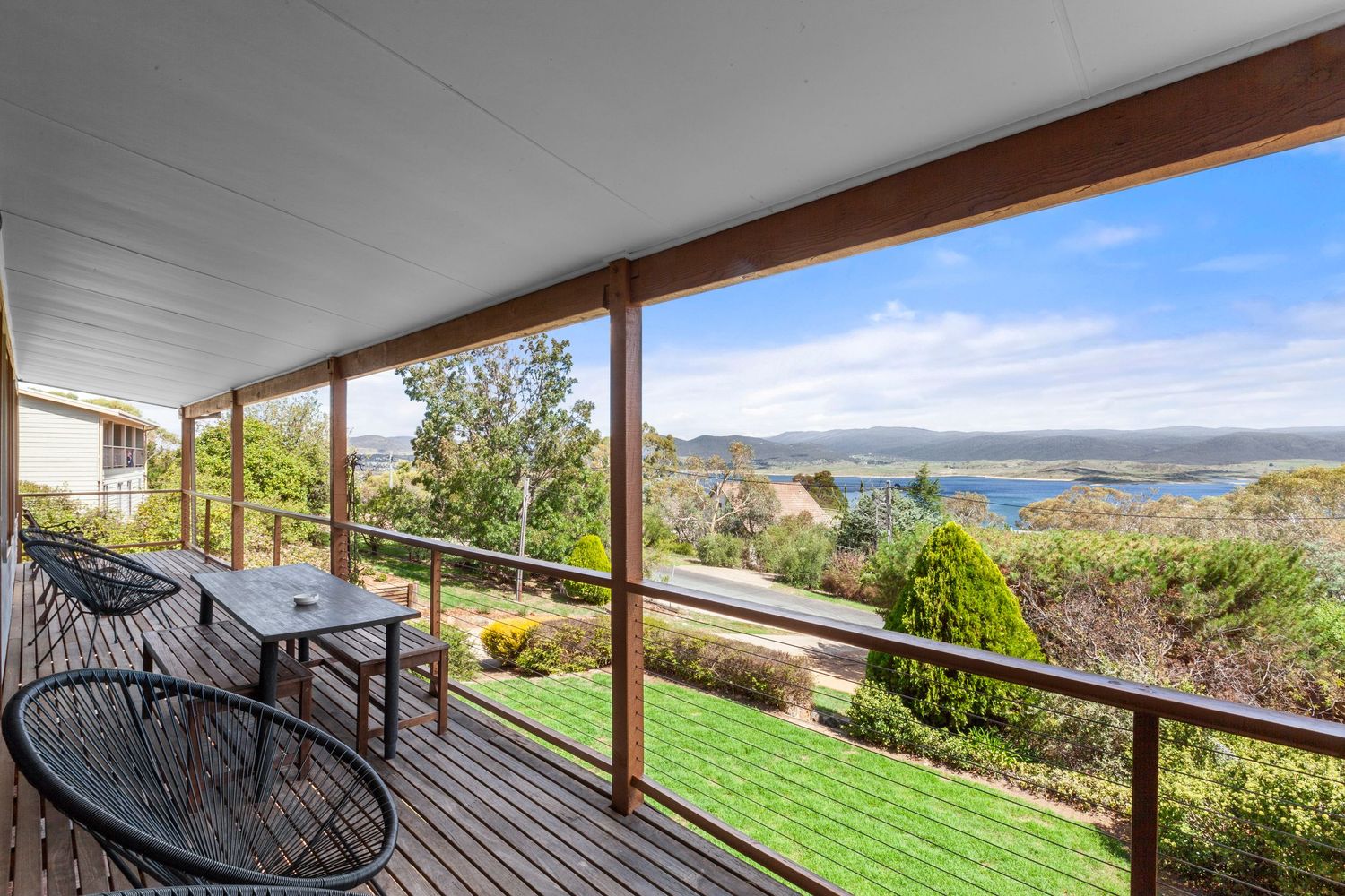 Expansive outdoor deck with wooden railings offering sweeping views of rolling hills and distant mountains.