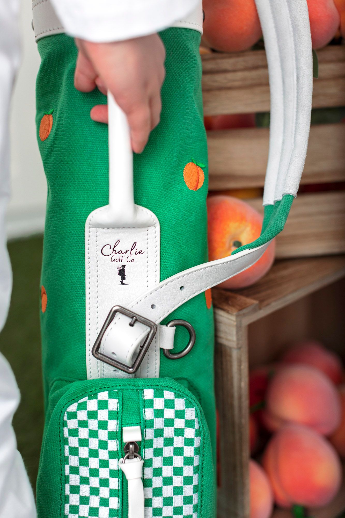 A green fabric bag with a black and white checkered pattern being held against a wooden background.