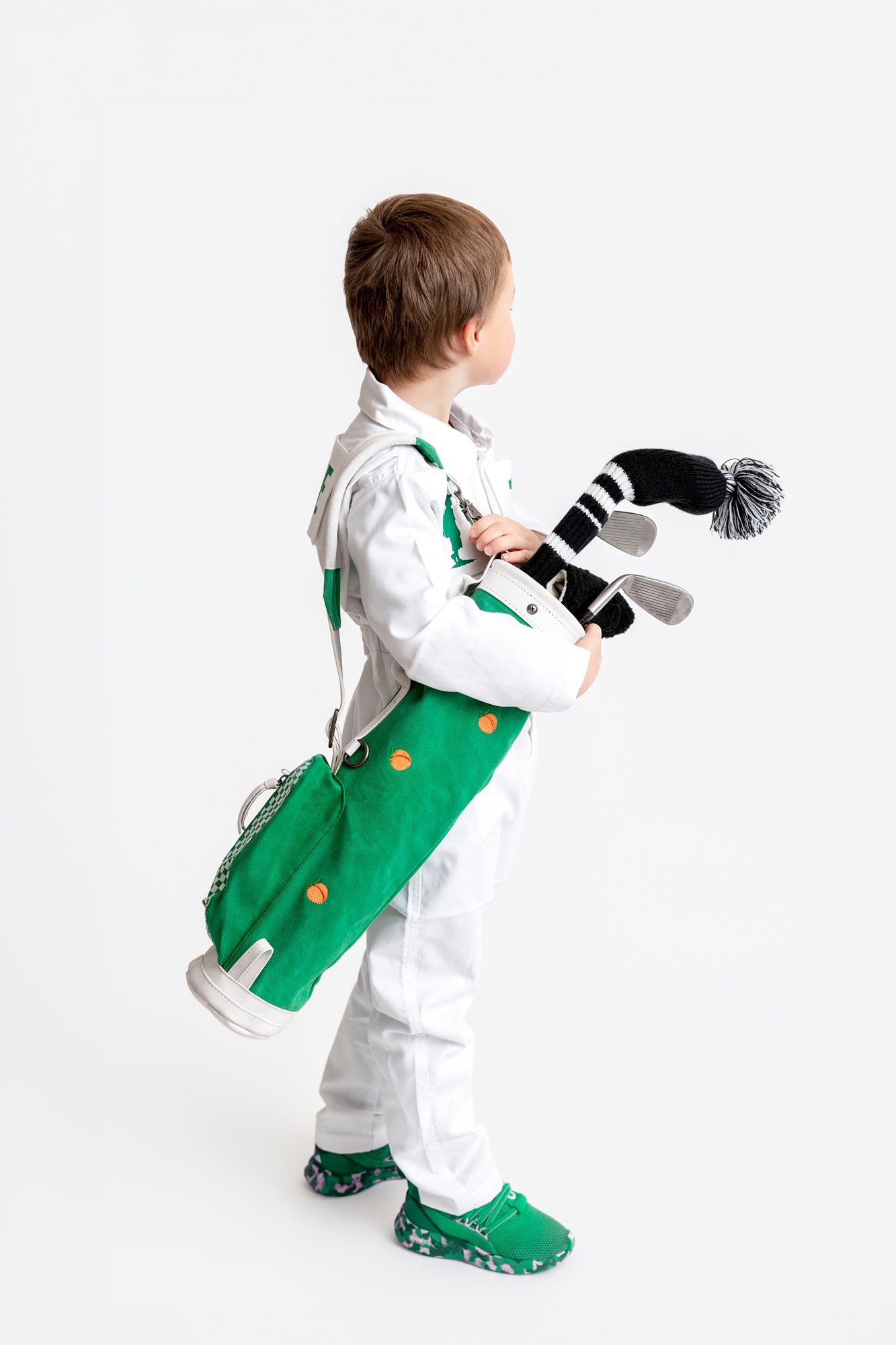 A toddler in a white shirt and green overalls dances and plays with a plush toy in three sequential poses.