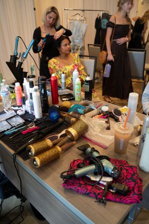 Hair styling tools and products arranged on a mirror behind the scenes at the 2026 Azalea Festival Spring Fashion Show