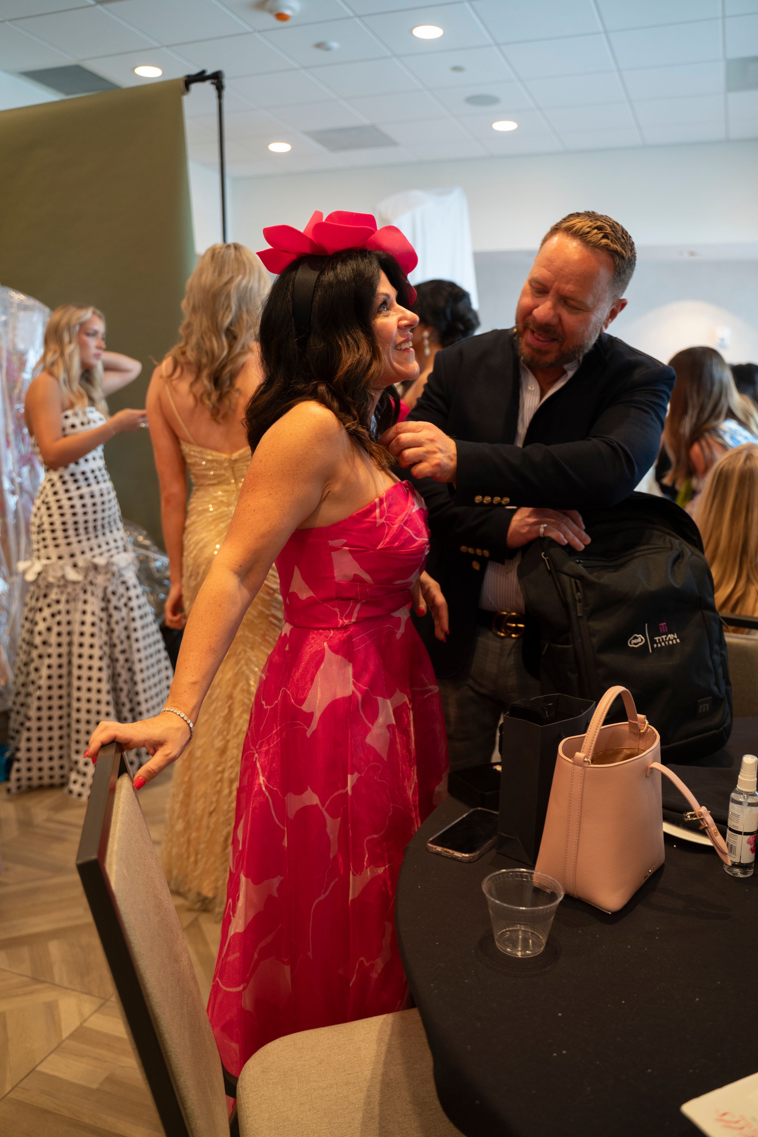 People mingling and dancing at a formal event with black and red attire visible.