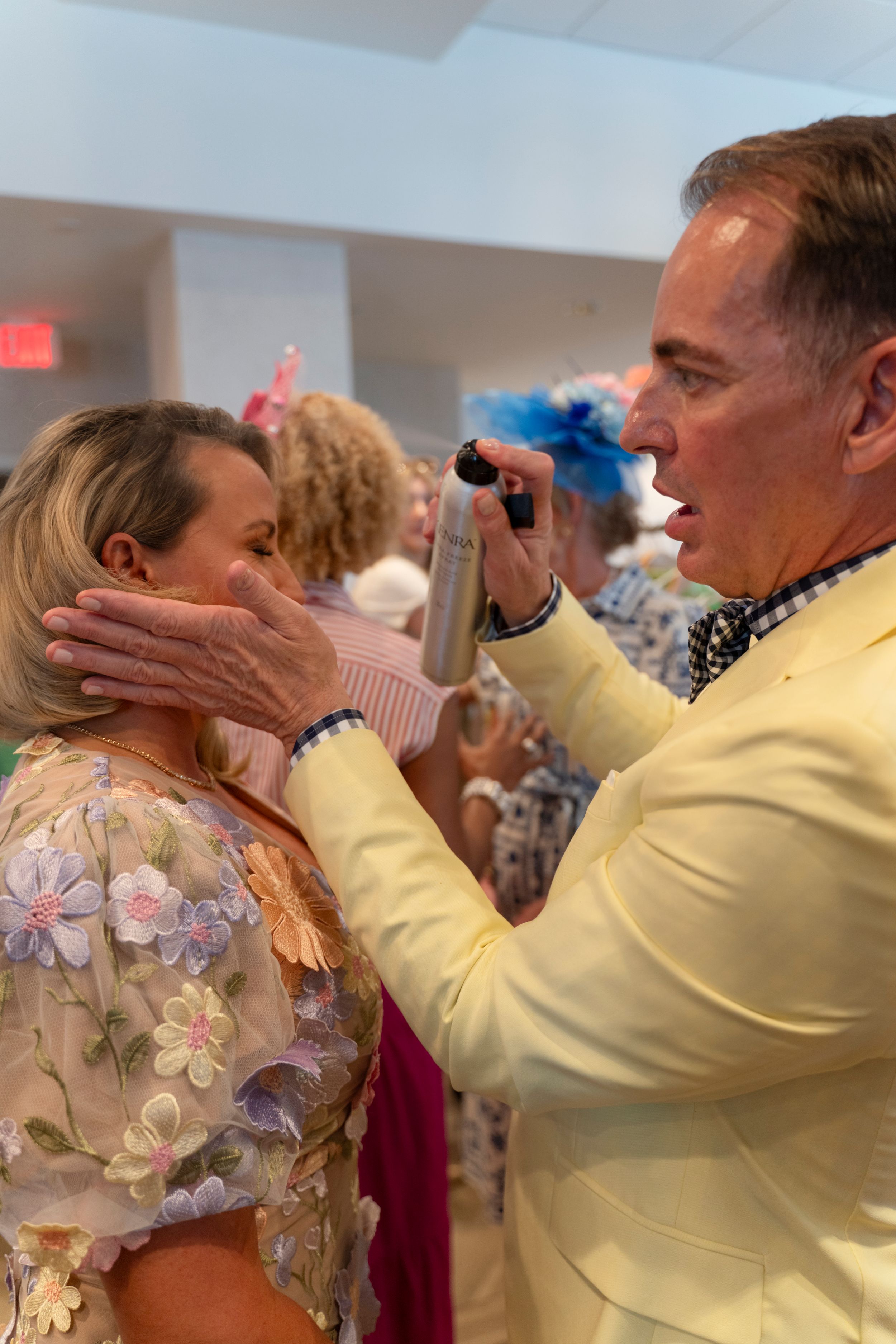 Multiple people in yellow attire and floral patterns participate in a styling or makeup session.