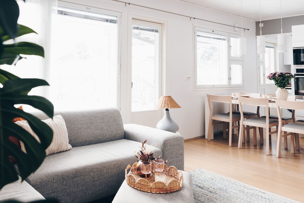 Bright and airy minimalist living room with white walls, wooden floors, and modern grey furniture.