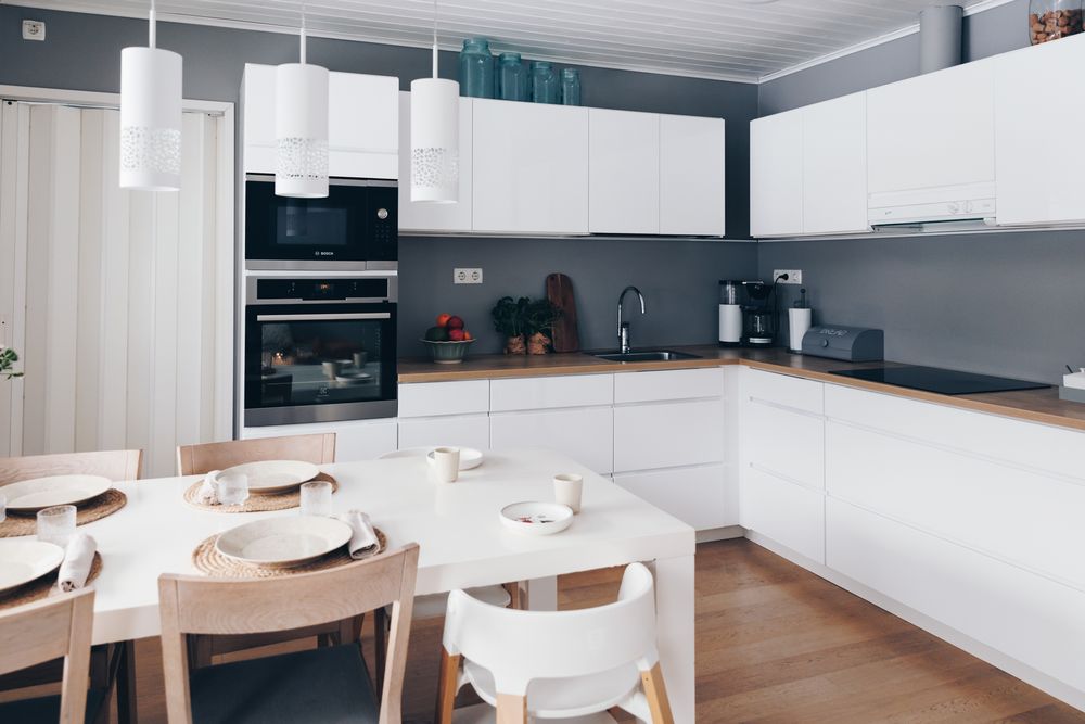 Modern open concept kitchen and dining area with white cabinets and dark accent wall.