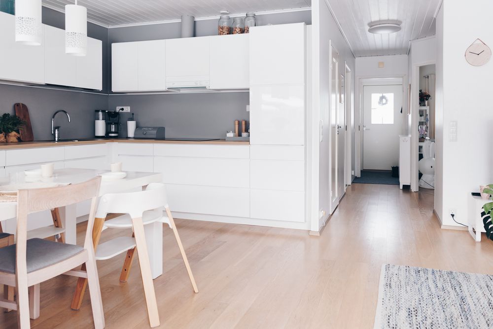 Modern white studio apartment interior with minimalist furniture and bright natural lighting throughout the space.