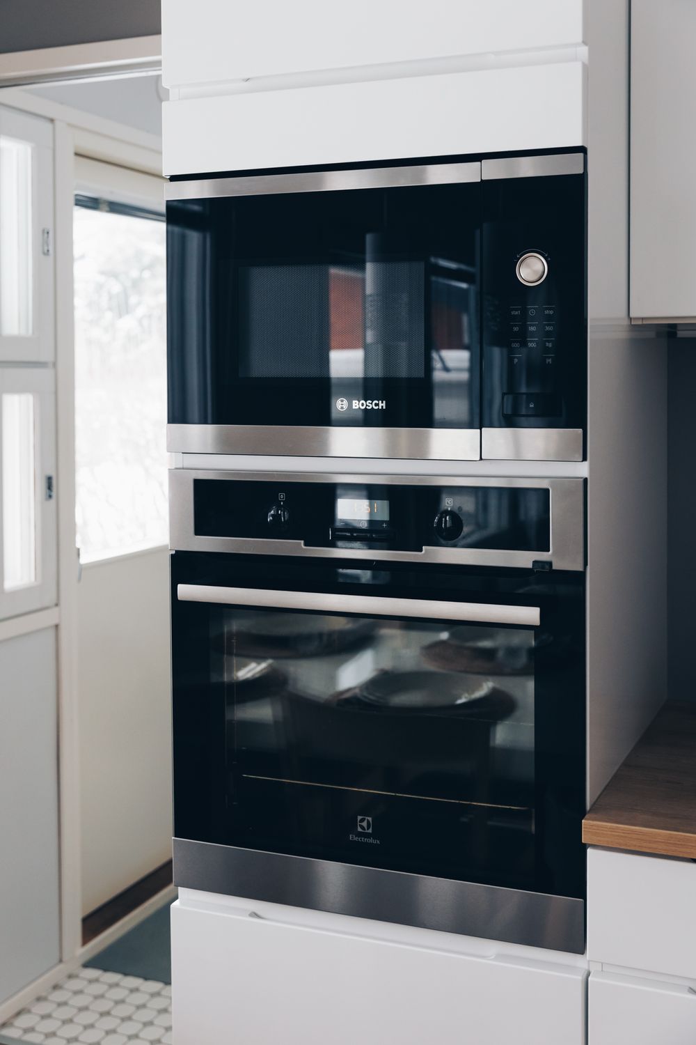 Modern black built-in microwave and oven combination installed in sleek white kitchen cabinetry.