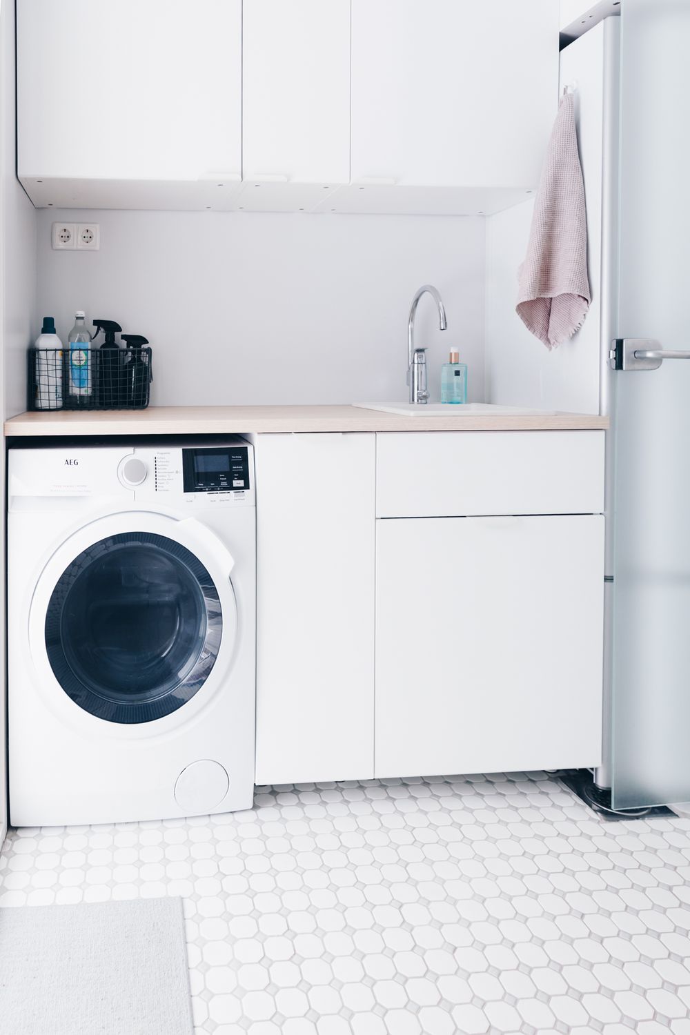 Modern white laundry room with washing machine, dryer, and geometric patterned floor tiles.