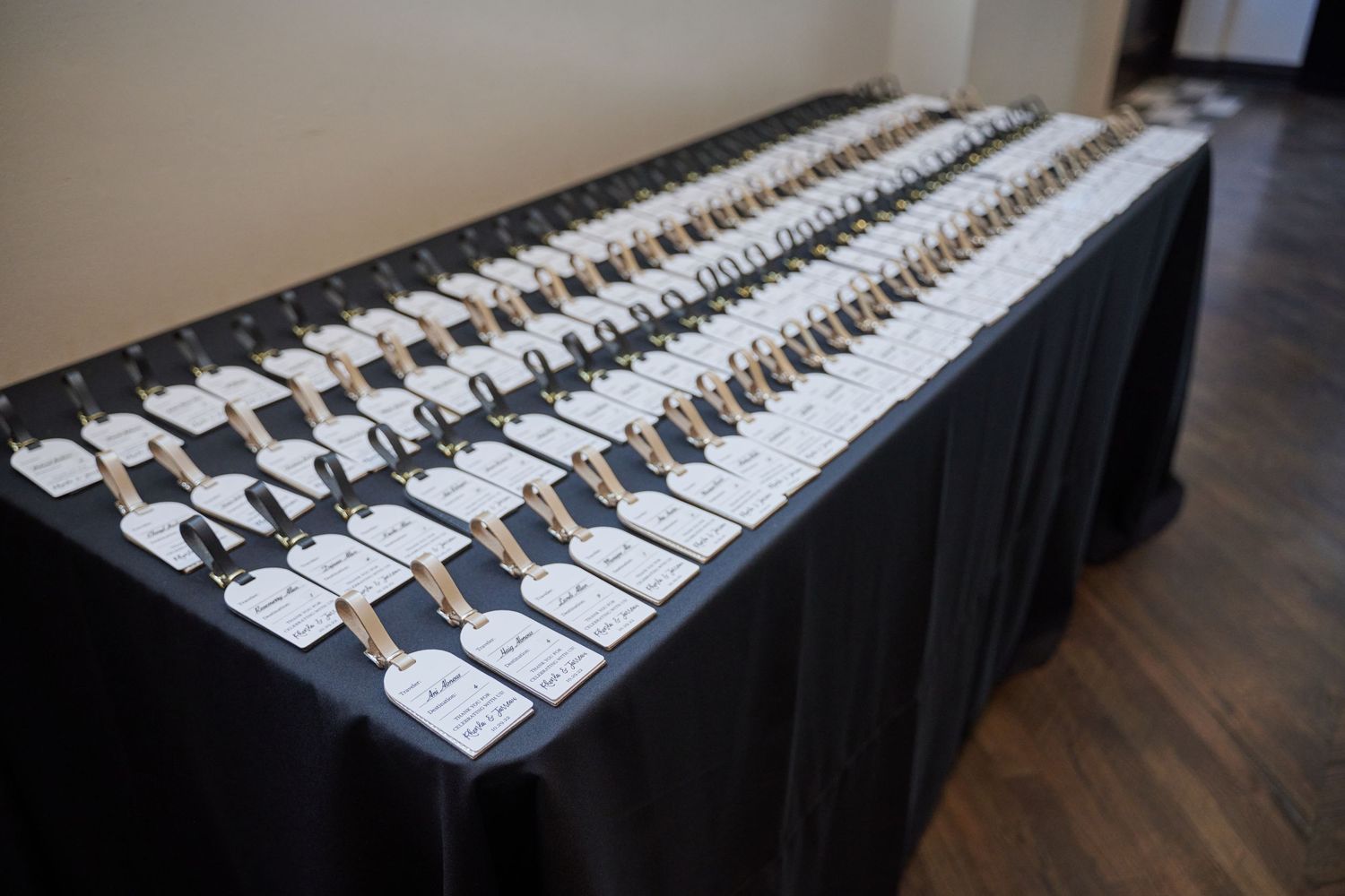 Long rows of white place cards with names arranged on black tablecloth for wedding reception seating.