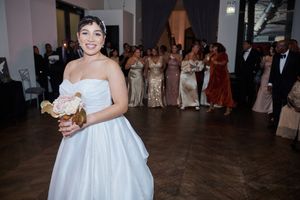 Wedding guests dance and celebrate on a dark wooden dance floor at an evening reception.