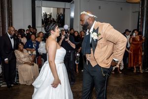 Wedding guests dance and celebrate on a crowded dance floor at an indoor reception venue.