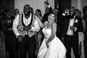 Wedding guests dance and celebrate together at an elegant reception party in black and white photography.