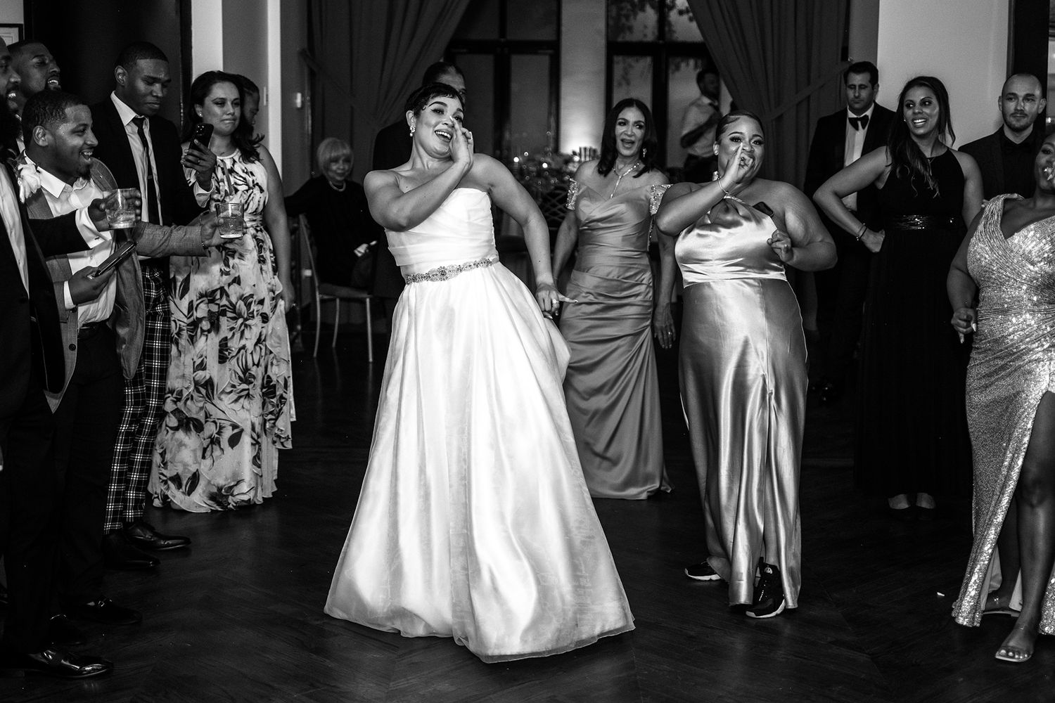 Wedding reception dance floor filled with guests celebrating in formal attire.