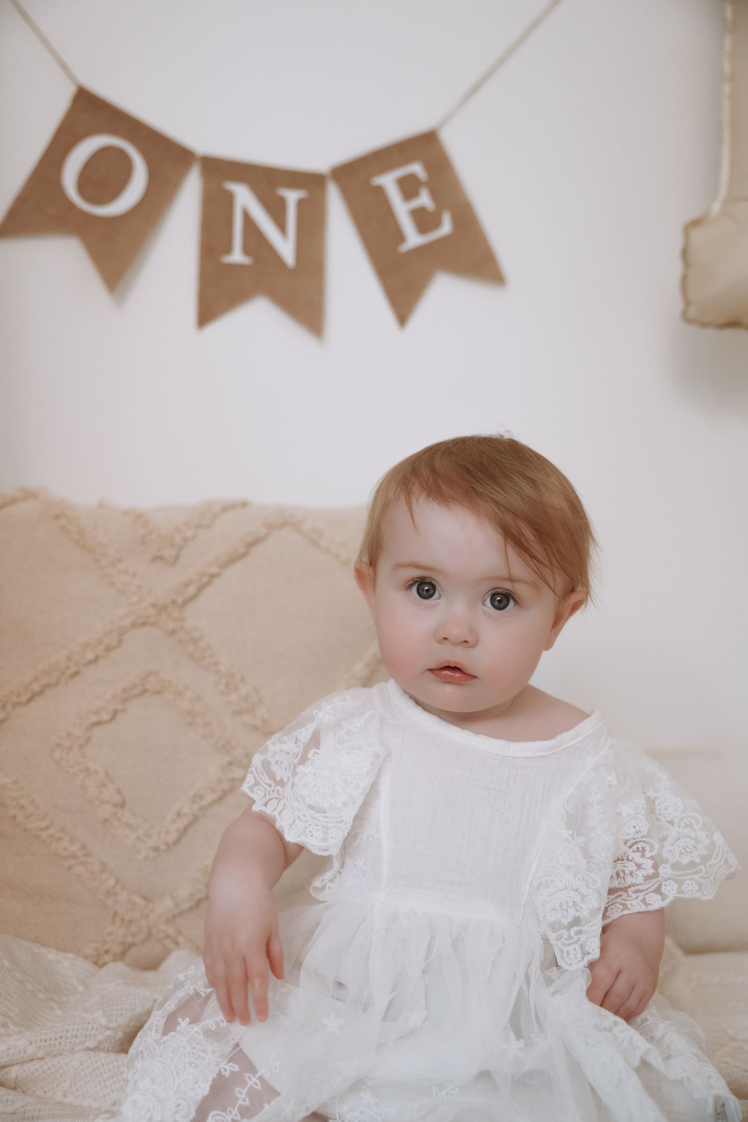 A family wearing matching denim and white outfits sits together on a white backdrop for a casual portrait session.