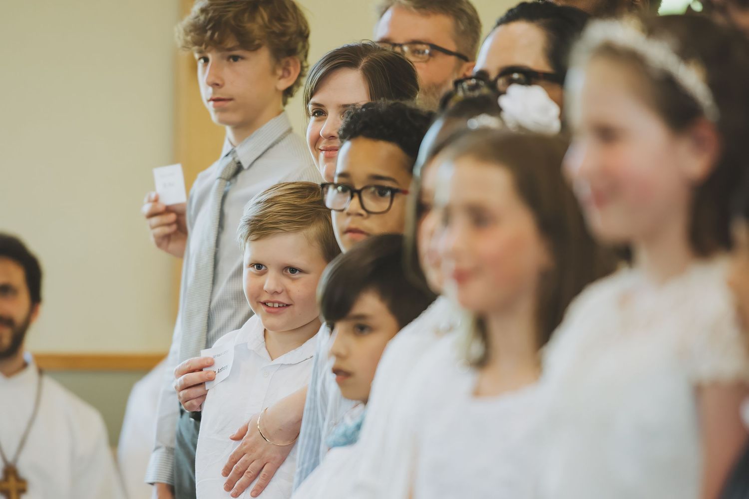 A group of students in white coats stand in a row during what appears to be a medical school ceremony.