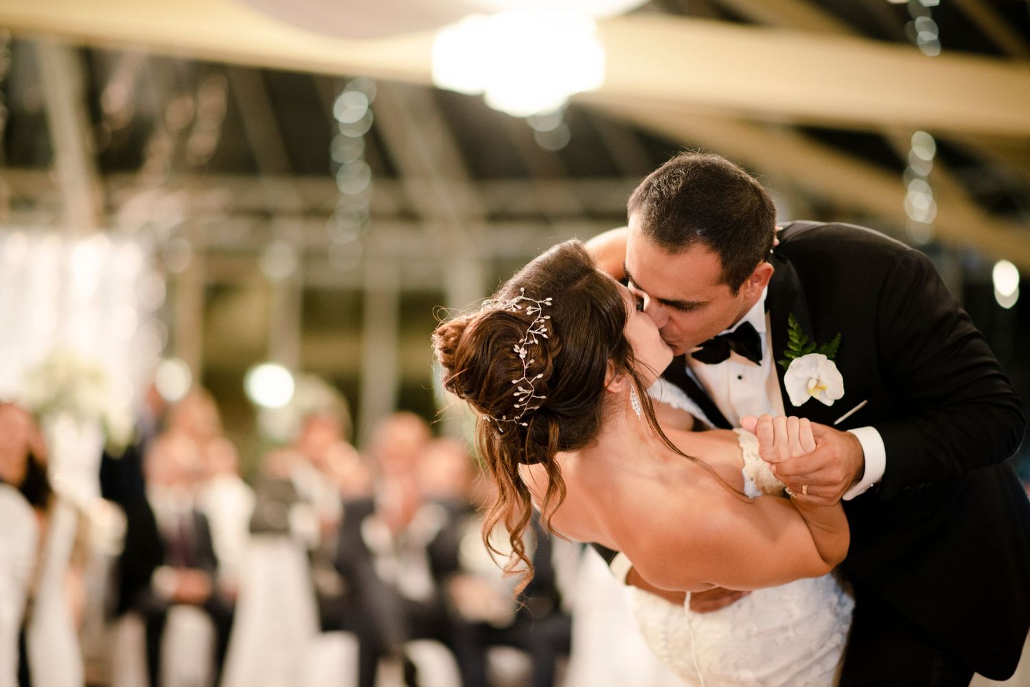 Bride and groom sharing a romantic first dance kiss at their elegant wedding reception.