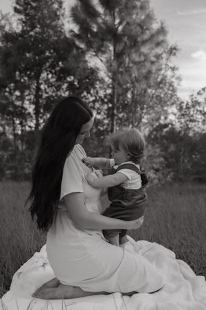 A couple lying in a grassy field shares tender moments in a sequence of black and white photos.