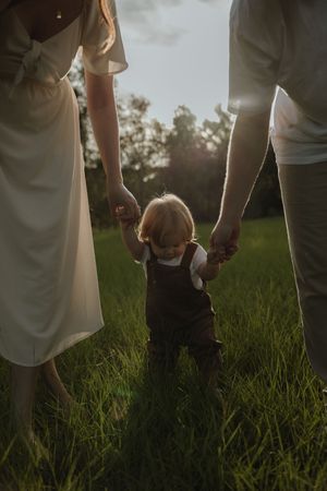 A sequence of photos showing feet walking through tall grass in a field at sunset.