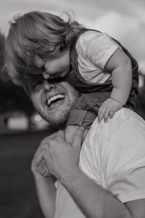 A heartwarming black and white photo series showing joyful moments between a parent and child playing together outdoors.