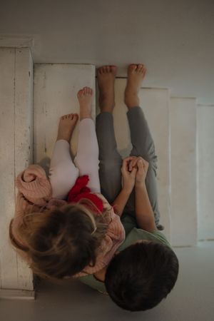 Two people lying on the floor with their feet up against a white wall, sharing a playful moment together.