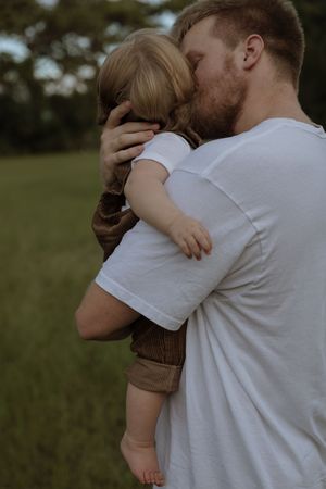 An intimate family embrace photographed against a natural outdoor backdrop at dusk.