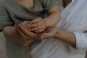 Close-up shot of two hands gently clasped together against a soft gray background.