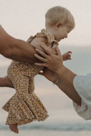 A sequence of photos showing hands gently holding and lifting a small child wearing a floral dress against a soft background.