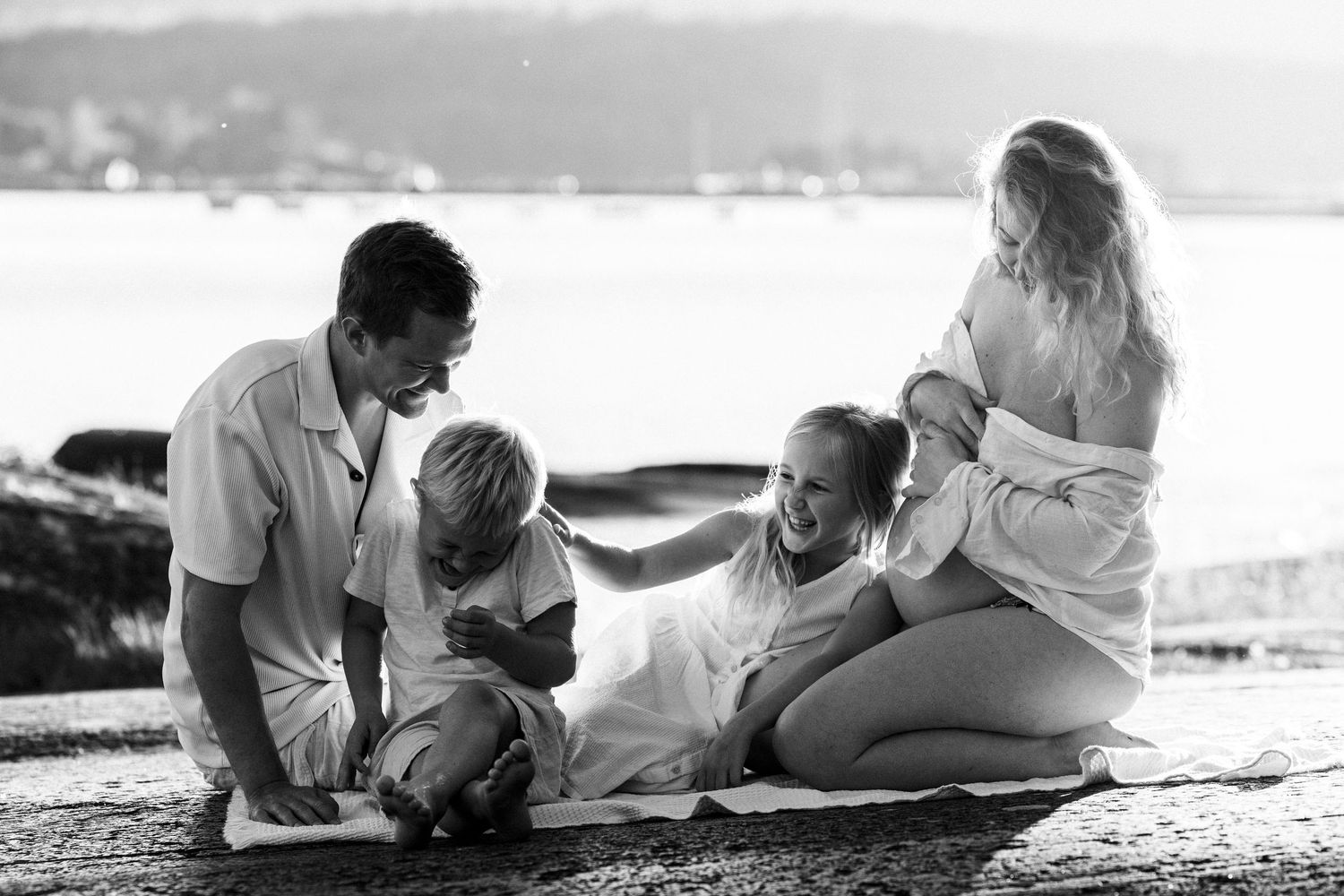 A series of black and white romantic beach photos showing couples laying together on the sand at sunset.