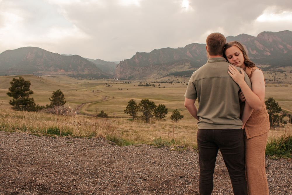 Couple embracing with scenic Colorado mountain landscape and golden fields in the background |What to Wear for Family Photos
