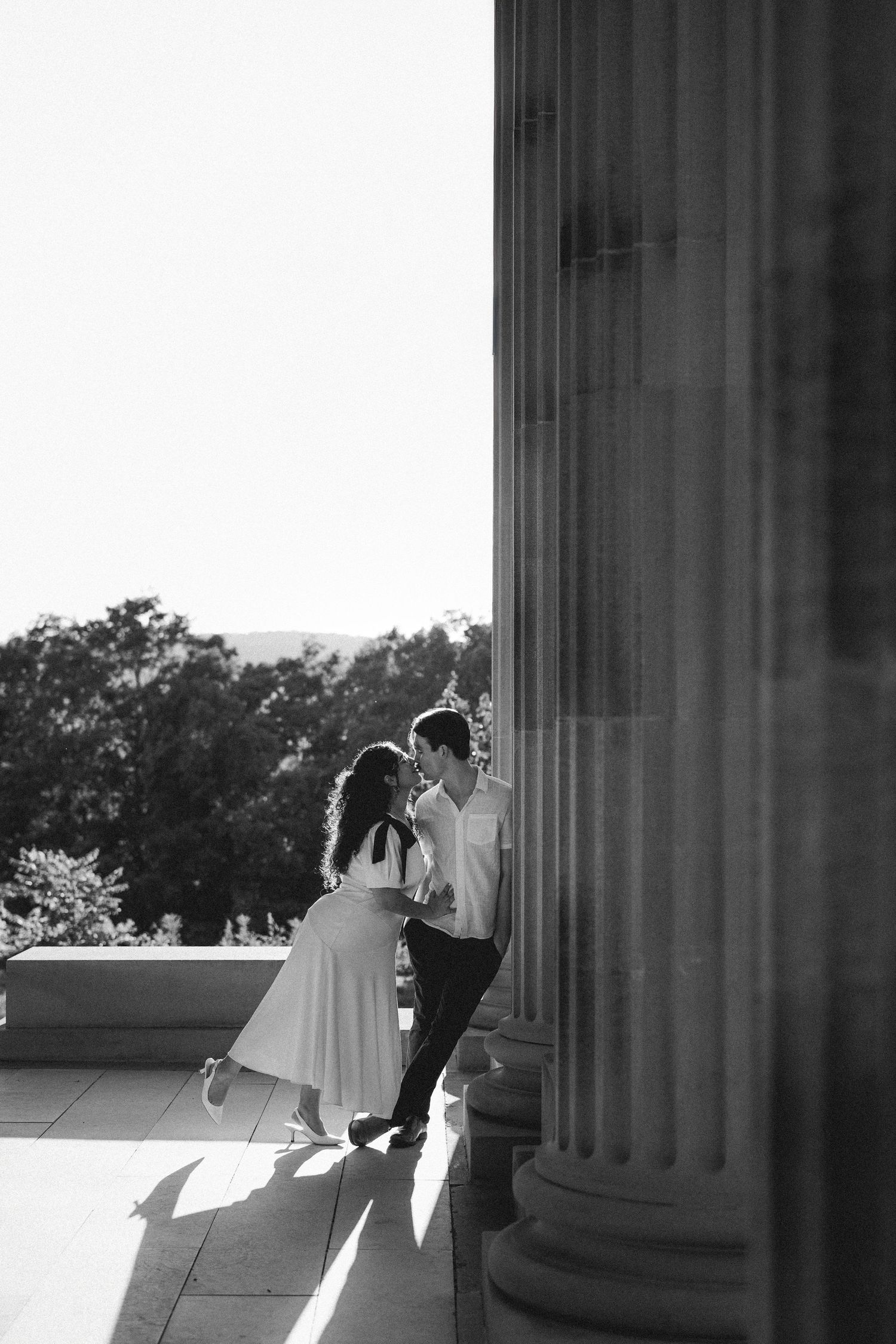 A romantic black and white wedding photo sequence showing a couple dancing between classical stone columns.
