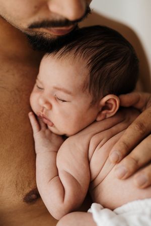 Warm toned close-up shots of sleeping newborn being cradled with care.