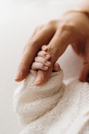 Macro detail shots of gentle hands touching soft knitted baby fabric.