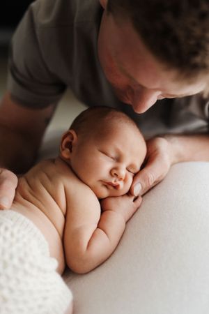 An intimate portrait of a sleeping newborn being tenderly watched.