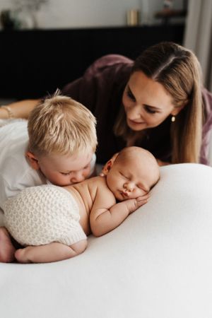 A touching moment as siblings share a gentle moment with their sleeping baby sibling.