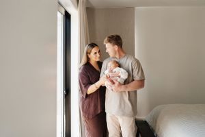 Family enjoying tender moments together in bright sunlit room near window.