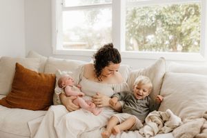 A bright living room scene with family members sharing intimate moments on a white sofa.